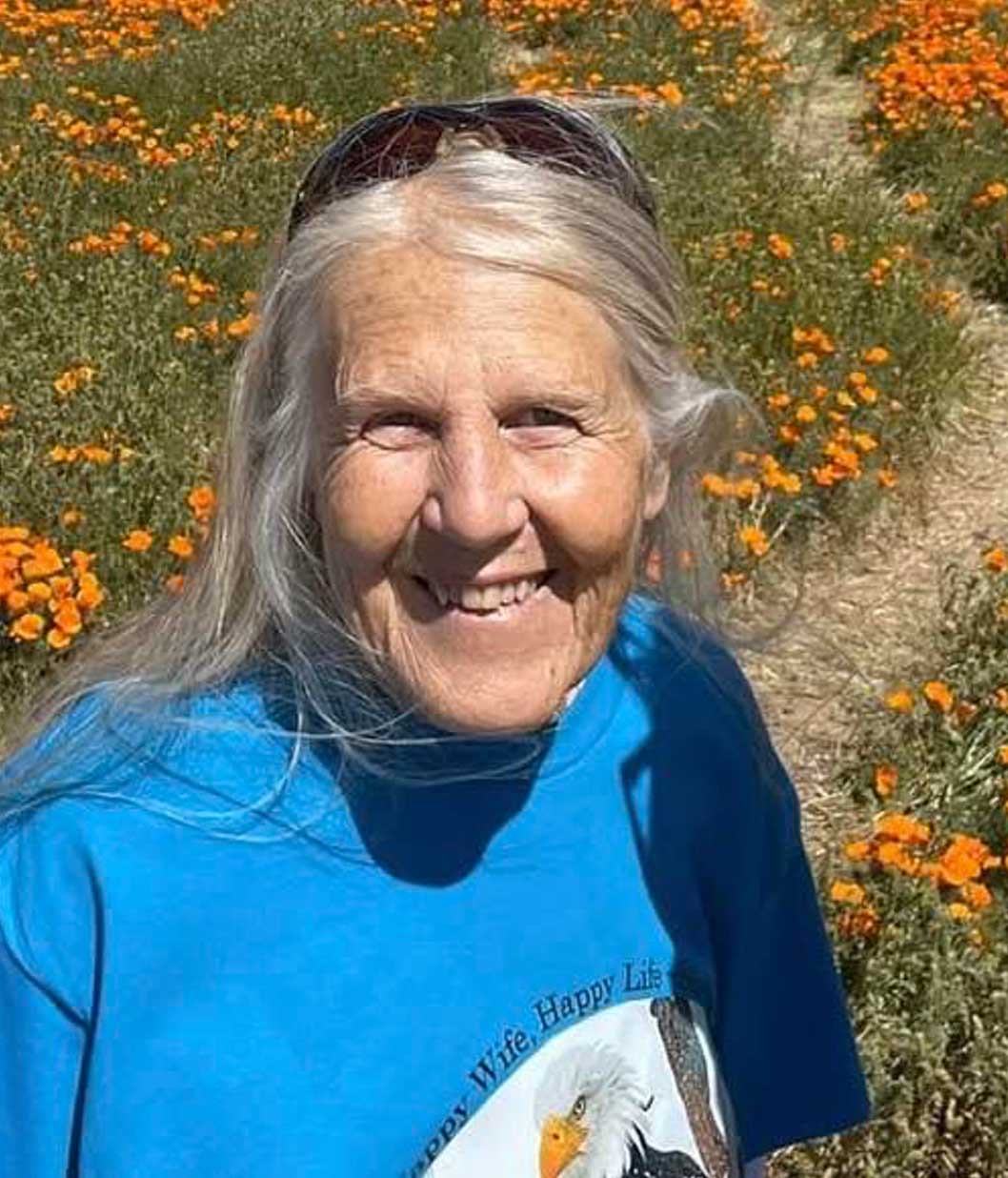 Sandy Steers standing among California poppies, smiling.